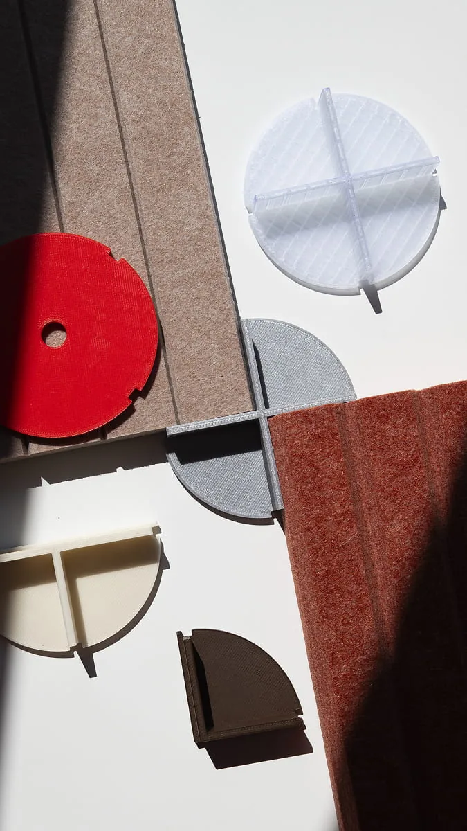 3D-gedruckte Viertelkreis-Wandmodule in Rot, Weiß, Grau, Creme und Braun neben Filz- und Teppichmustern