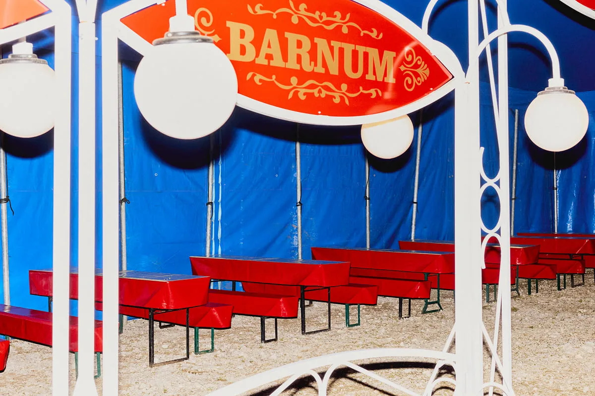Kind in Artistenkostüm balanciert auf einer Kugel in der Manege vor nächtlichem Sternenhimmel-Kulisse