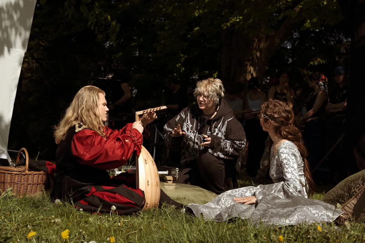 Filmteam bereitet bei Kerzenlicht eine festlich gedeckte historische Tafel mit Kronleuchter und Kandelabern vor